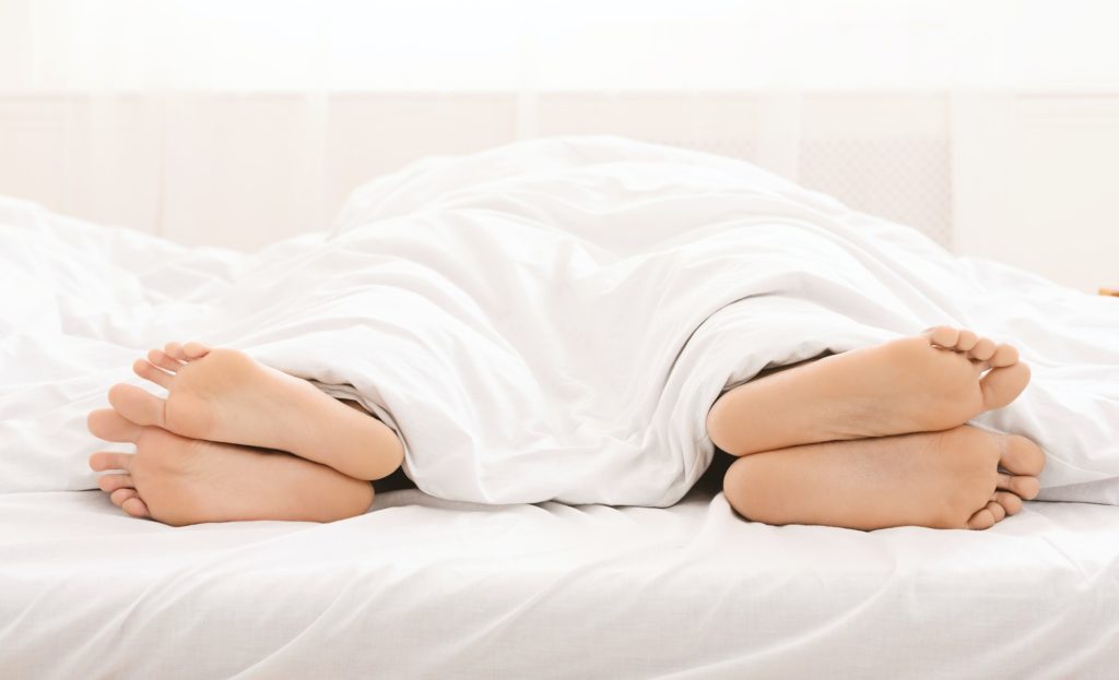 Bare feet of couple sleeping separately in bed